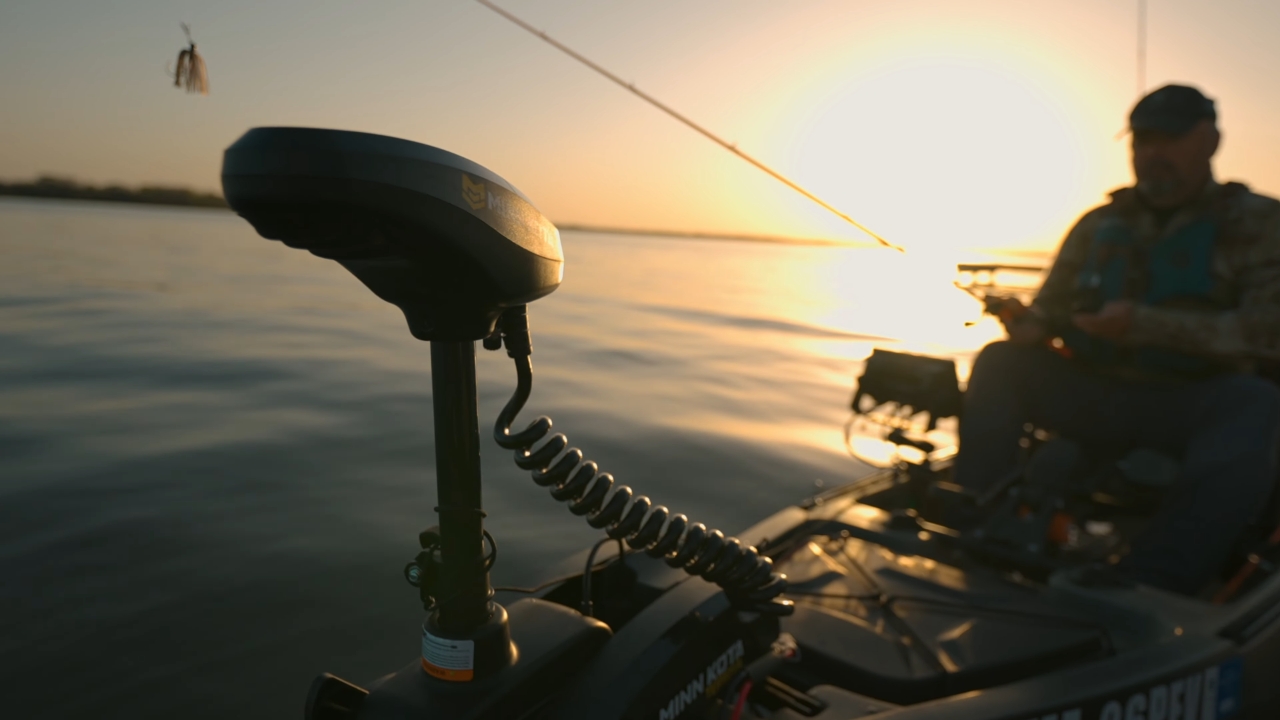 Close-up of a kayak trolling motor at sunset with an angler in the background
