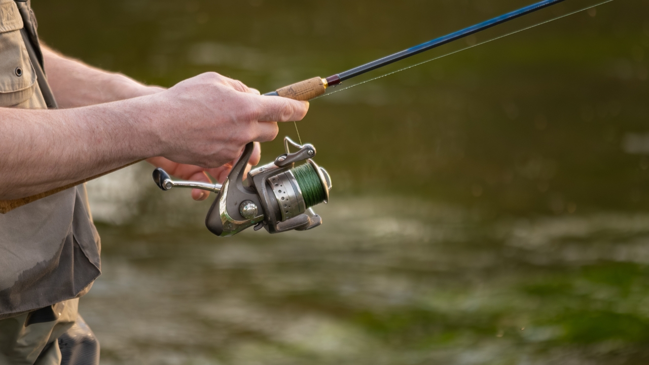 Angler holds a spinning reel close to the water