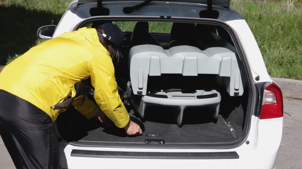 Person loading a modular fishing kayak into the back of a car